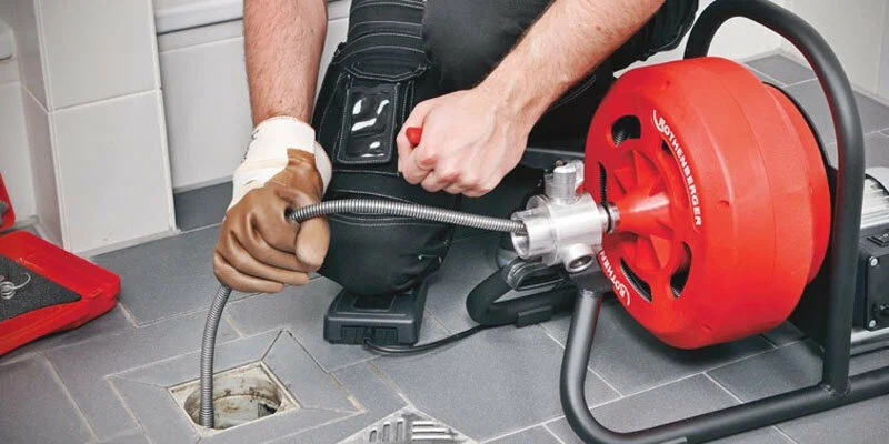 Plumber using a drain-cleaning machine in Loveland