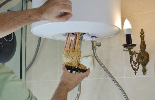 Technician removing mineral buildup from a water heater in Loveland