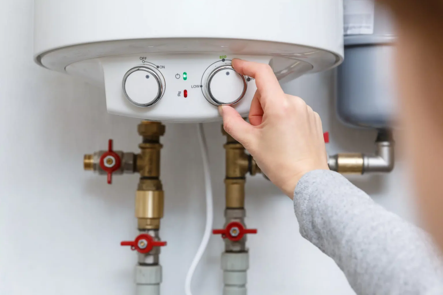 Homeowner adjusting the temperature controls on a water heater in Loveland